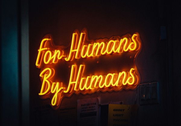 Jon tyson tEVKC91Qm6c unsplash. A neon sign saying For Humans By Humans