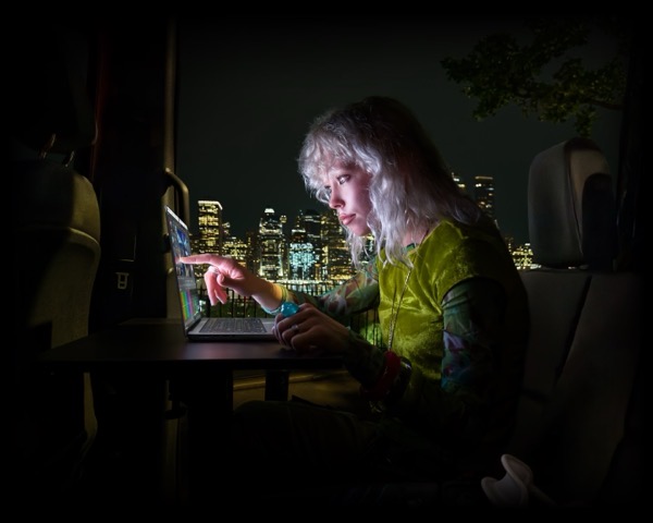 Apple PR Image of a young woman using a touch screen MacBook Pro with a city skyline at night in the background  c8gxlalyqeie large 2x.